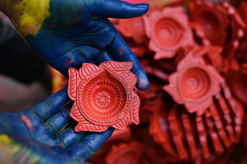 Seorang pembuat tembikar menunjukkan lampu tanah jelang Festival Diwali di sepanjang pinggir jalan di New Delhi, India, 18 Oktober 2022.