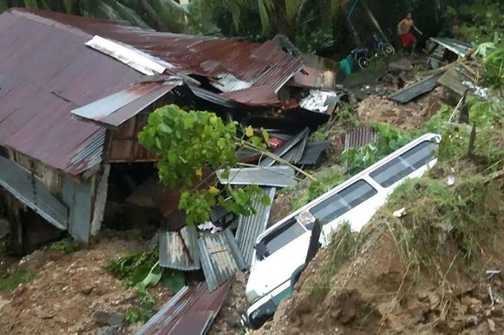 Seorang warga berdiri di samping rumah dan kendaraan yang rusak setelah tanah longsor akibat hujan lebat yang dibawa oleh Badai Tropis Nalgae menerjang Kota Parang, Provinsi Maguindanao, Filipina selatan.