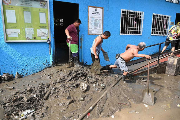 Ketika tim penyelamat terus mencari korban yang belum ditemukan, para penyintas melanjutkan tugas mereka untuk membersihkan rumah dari endapan lumpur.