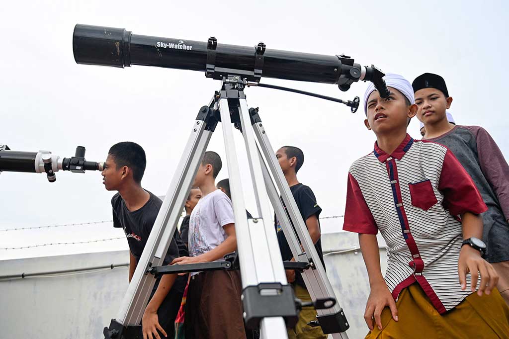 Santri dan masyarakat umum mengamati proses terjadinya gerhana bulan total dengan menggunakan teleskop di Ajun, Aceh Besar, Aceh, Selasa, 8 November 2022. AFP PHOTO/Chaideer Mahyuddin