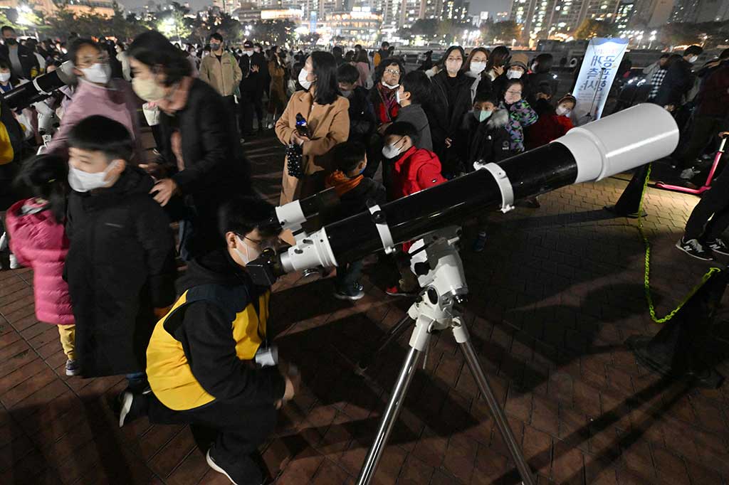 Warga menyaksikan bulan darah melalui teleskop saat gerhana bulan total di Goyang, barat laut Seoul, Korea Selatan, pada Selasa, 8 November 2022. AFP PHOTO/Jung Yeon-Je