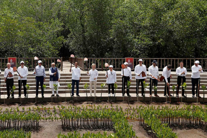 Presiden Joko Widodo bersama para kepala negara/kepala pemerintahan negara anggota G20 dan pimpinan organisasi internasional mengangkat pacul usai menanam mangrove di Tahura Ngurah Rai, Denpasar, Bali.