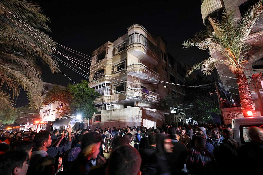 Massa berkerumun di jalan di luar rumah bertingkat saat api berkobar, mengirimkan gumpalan asap mengepul keluar dari atas gedung.