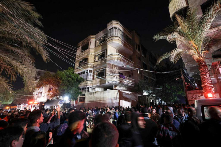 Massa berkerumun di jalan di luar rumah bertingkat saat api berkobar, mengirimkan gumpalan asap mengepul keluar dari atas gedung.