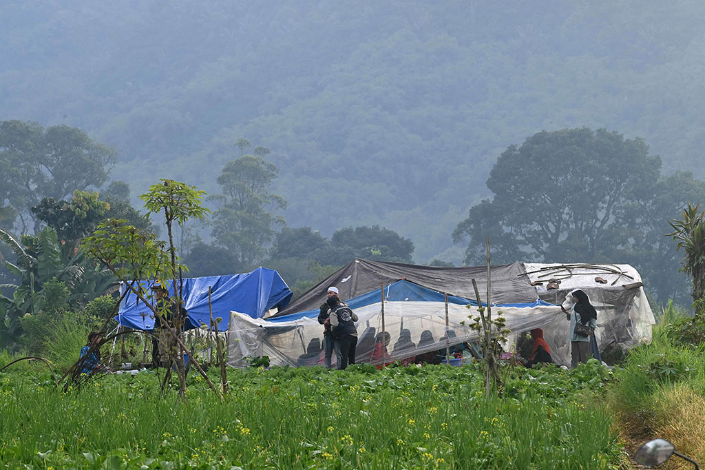 Terlihat puluhan warga dan balita berlindung di tenda darurat yang didirikan di pinggir sawah.