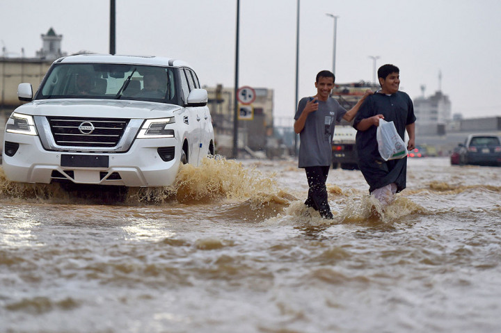 Warga berjalan di jalan yang banjir setelah hujan deras melanda Kota pesisir Jeddah, Arab Saudi pada Kamis, 24 November 2022.