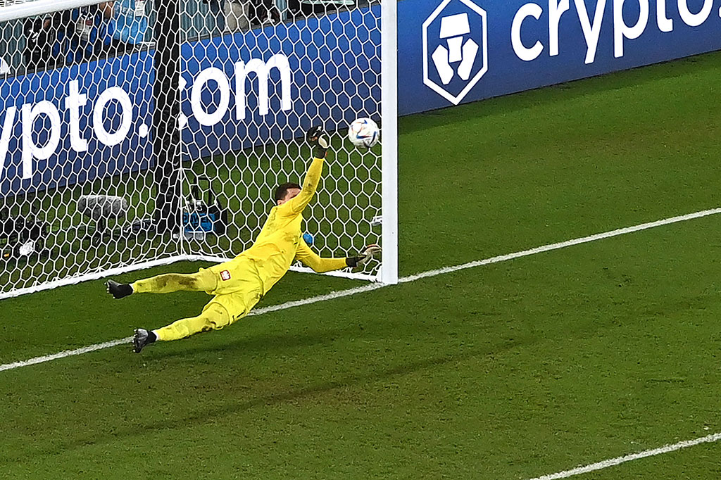 Szczesny menepis bola sepakan Messi dengan tangan kanannya.