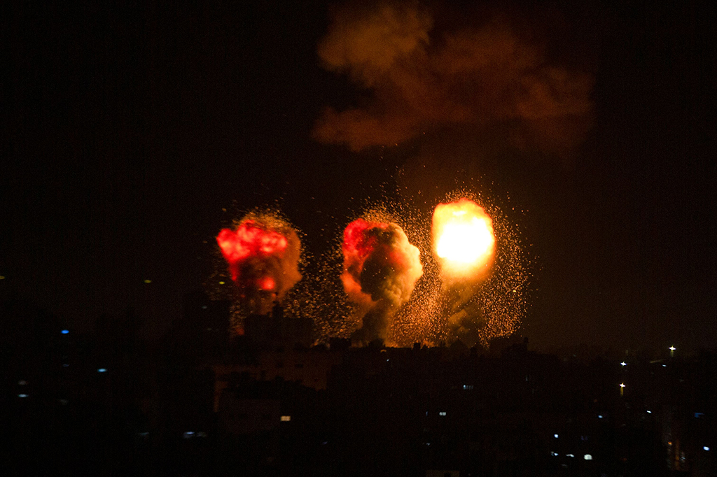 Bola api dan kepulan asap membubung di atas gedung-gedung di selatan jalur Akota saat pesawat tempur Israel menargetkan daerah kantong Palestina, Minggu, 4 Desember 2022 malam.