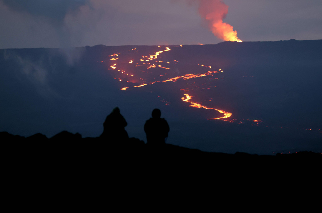 Orang-orang menyaksikan letusan gunung berapi Mauna Loa di dekat Hilo, Hawaii pada Minggu, 4 Desember 2022. Untuk pertama kalinya dalam hampir 40 tahun, Mauna Loa, gunung berapi aktif terbesar di dunia, meletus dan menimbulkan pertunjukan spektakuler.