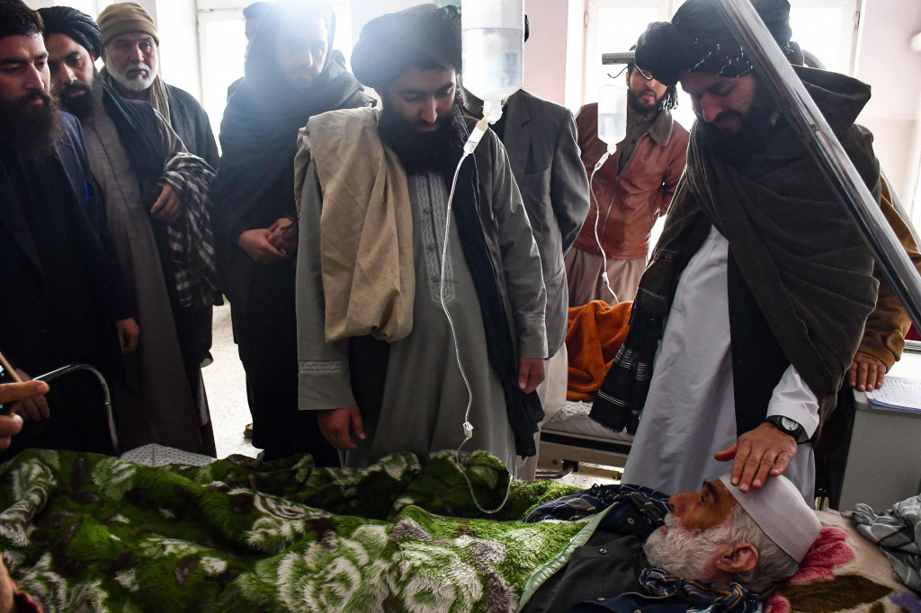 Anggota pasukan keamanan Taliban membezuk seorang pria yang dirawat di rumah sakit akibat luka-lukanya setelah sebuah bom pinggir jalan menghantam sebuah bus yang membawa karyawan sebuah perusahaan minyak di Mazar-i-Sharif, Afghanistan, pada Selasa, 6 Desember 2022.