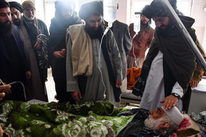 Anggota pasukan keamanan Taliban membezuk seorang pria yang dirawat di rumah sakit akibat luka-lukanya setelah sebuah bom pinggir jalan menghantam sebuah bus yang membawa karyawan sebuah perusahaan minyak di Mazar-i-Sharif, Afghanistan, pada Selasa, 6 Desember 2022.