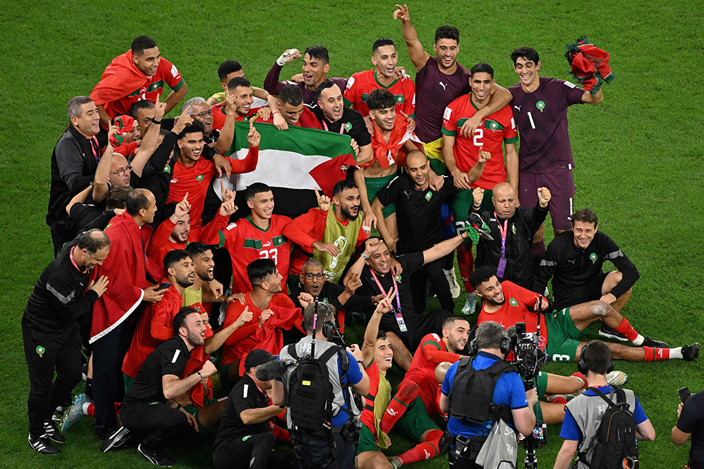 Para pemain maroko dan staf berfoto bersama sambil memegang bendera Palestina usai memastikan diri melaju ke babak perempat final Piala Dunia 2022.