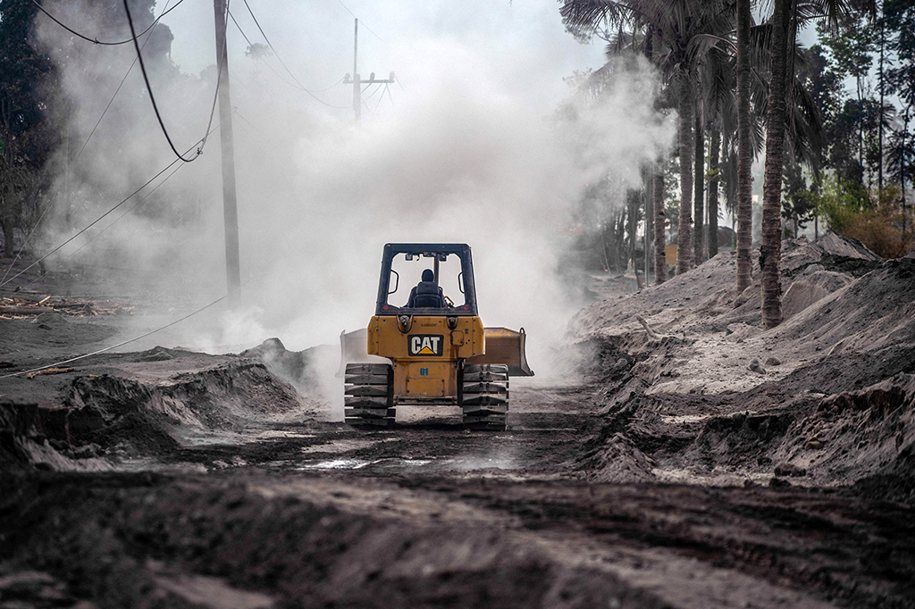 Pembersihan material yang menutupi jembatan dan badan jalan tersebut agar bisa dilalui warga. Meski dinyatakan sebagai wilayah zona merah, sejumlah warga terlihat menyaksikan petugas membersihkan material akibat APG Semeru.