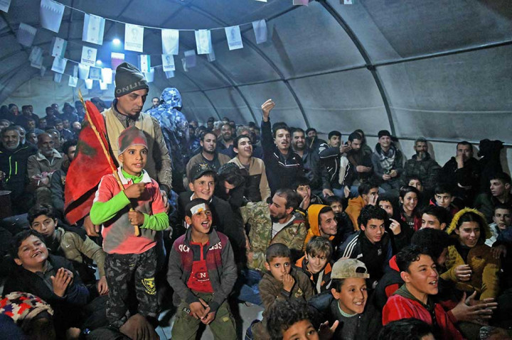 Penggemar sepak bola berkumpul di dalam tenda raksasa di kamp Deir al-Ballut di wilayah Afrin di provinsi Aleppo utara yang dikuasai pemberontak Suriah, bereaksi saat mereka menyaksikan pertandingan semifinal antara Prancis dan Maroko, selama turnamen Piala Dunia Qatar 2022 pada Desember 14, 2022. AFP PHOTO/Rami al Sayed
