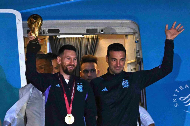 Messi dan sang pelatih Lionel Scaloni keluar dari pesawat lebih dahulu sambil memegang trofi Piala Dunia.