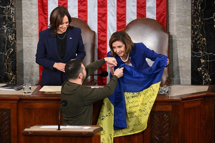 Presiden Ukraina Volodymyr Zelensky memberikan bendera pertempuran Ukraina kepada Ketua DPR AS Nancy Pelosi kanan dan Wakil Presiden Kamala Harris saat berpidato di pertemuan gabungan Kongres di di Washington, DC, Rabu, 21 Desember 2022 waktu setempat.