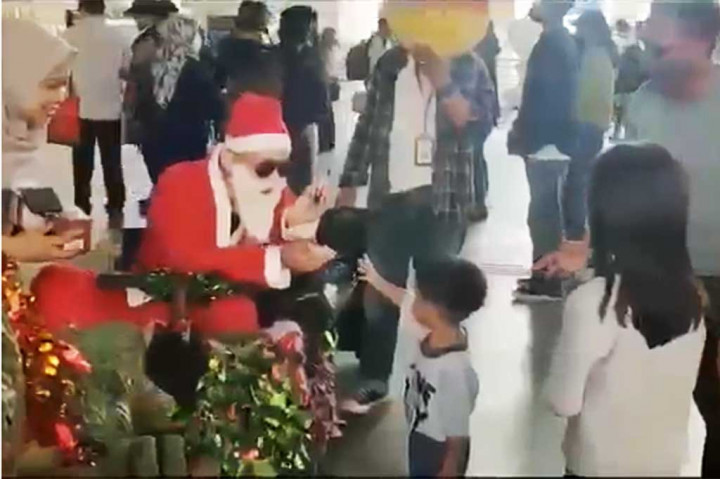 Sinterklas memberikan kue dan makanan kecil kepada calon penumpang pesawat di dekat dekorasi Natal di Terminal 2 Bandara Soekarno Hatta, Tangerang, Banten, Sabtu, 24 Desember 2022.