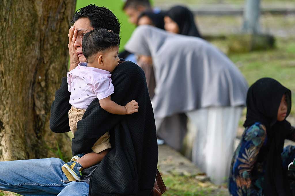 Seorang warga tak kuasa menahan tangis saat berziarah dan berdoa di kuburan massal korban tsunami di Banda Aceh, Senin, 26 Desember 2022.