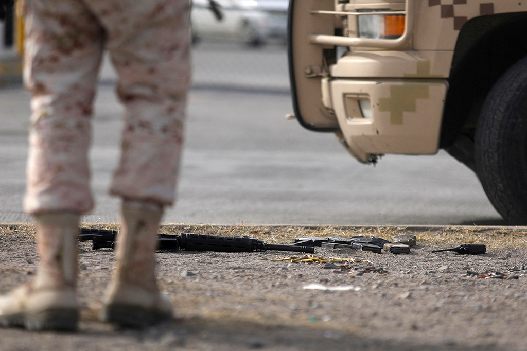 Seorang anggota tentara Angkatan Darat Meksiko berdiri di samping senapan semi-otomatis dan selongsong peluru yang ditemukan di luar penjara Ciudad Juarez pascaserangan bersenjata, di negara bagian Chihuahua, Meksiko pada Minggu, 1 Januari 2023 waktu setempat.
