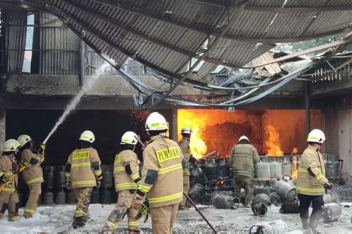 Petugas berusaha memadamkan api yang melalap gudang gas elpiji dan distributor briket batubara di kawasan Pondok Kelapa, Duren Sawit, Jakarta Timur, Jumat, 27 Januari 2023 pagi. Ledakan mewarnai kebakaran tersebut.