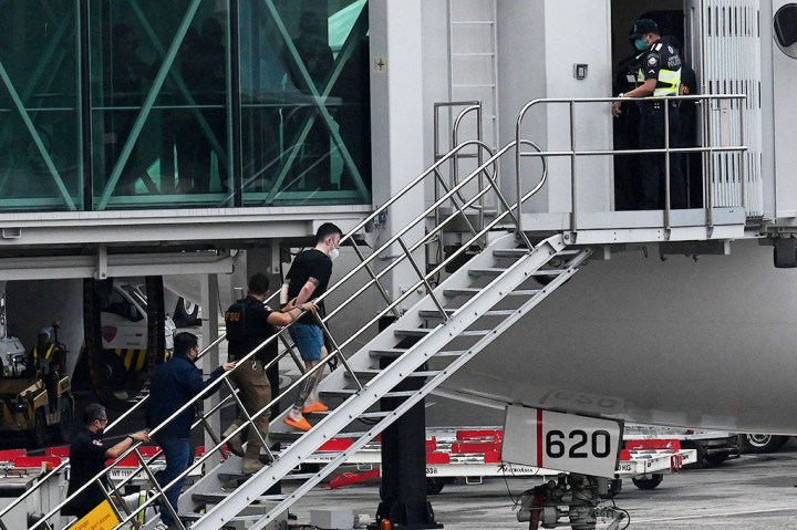 Petugas mengawal Kiyoto Imamura dan Toshiya Fujita, yang keduanya diborgol, ke dalam jet Japan Airlines di bandara Manila.