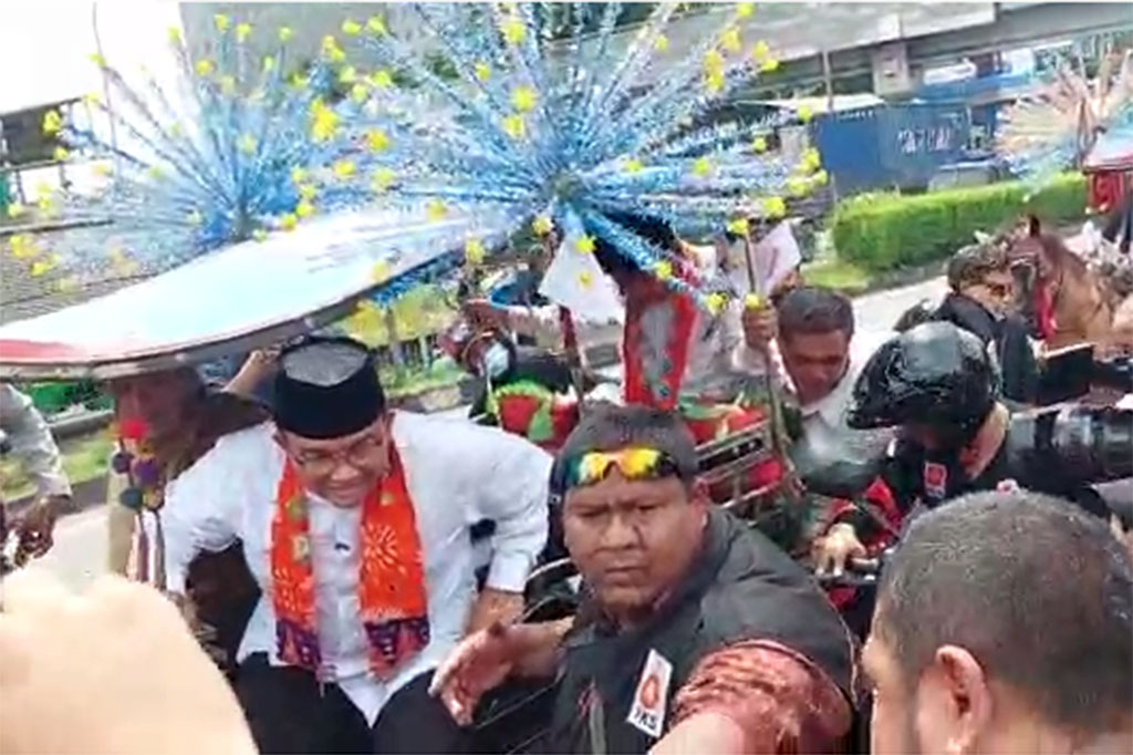 Prosesi pengantaran Anies disusul iring-iringan drumband ketika mendekati Kantor DPP PKS. Anies tampak mengenakan baju koko berwarna putih dengan selendang berwarna oranye.