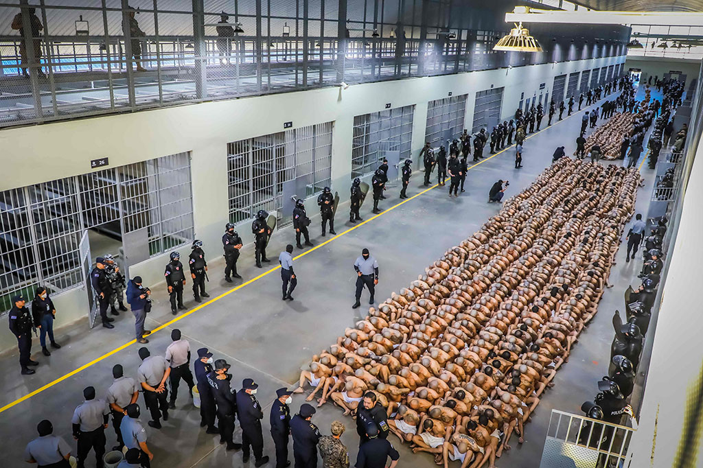 Presiden memposting video yang memperlihatkan pria bertelanjang kaki bertato yang hanya mengenakan celana pendek putih, membungkuk dan dengan tangan di belakang kepala yang gundul.