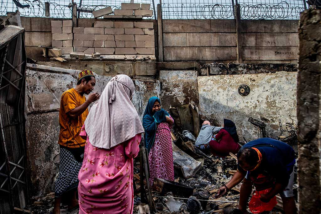 Warga mengais untuk mencari barang-barang yang masih bisa diselamatkan di antara puing-puing rumah mereka yang hangus terbakar.