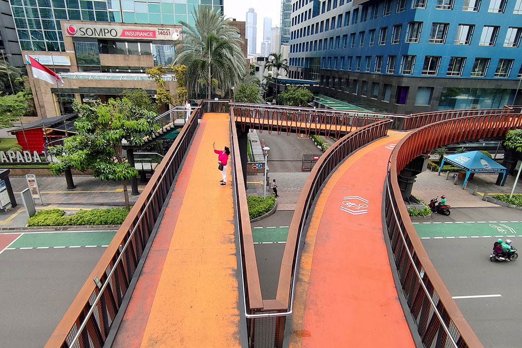 Seorang perempuan terlihat mengabadikan jalanan lengang di Jalan Jenderal Sudirman dari jembatan penyeberangan orang.