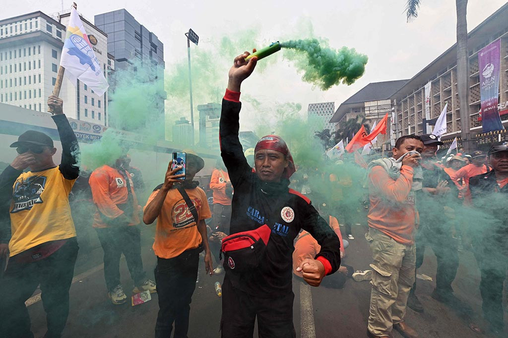 Puluhan bus yang mengangkut massa aksi menuju lokasi dan sebuah mobil komando berada di depan massa yang bernyanyi diiringi mars Partai Buruh untuk menggugah semangat.    