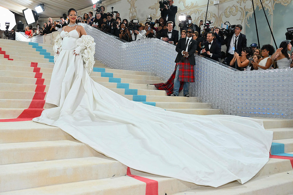 Superstar pop Rihanna mengenakan gaun putih Valentino, dengan kamelia yang lapang - bunga yang identik dengan Chanel - menghiasi tudung jubahnya. Sarung tangan tanpa jari putihnya mencerminkan yang disukai oleh Lagerfeld. Di bawah? Gaun putih seksi dengan tali spaghetti.