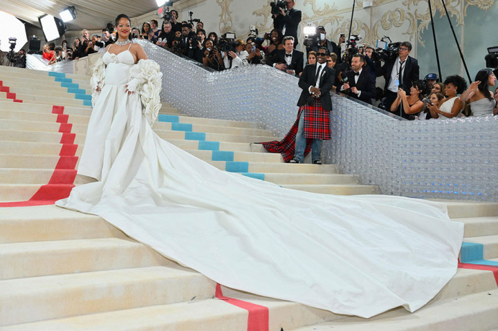 Superstar pop Rihanna mengenakan gaun putih Valentino, dengan kamelia yang lapang - bunga yang identik dengan Chanel - menghiasi tudung jubahnya. Sarung tangan tanpa jari putihnya mencerminkan yang disukai oleh Lagerfeld. Di bawah? Gaun putih seksi dengan tali spaghetti.