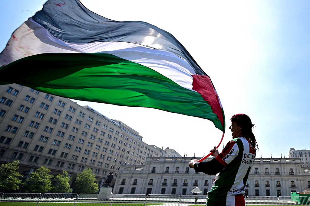 Ribuan mil jauhnya dari konflik di Timur Tengah, bendera Palestina berkibar pada malam musim gugur yang dingin di sebuah stadion sepak bola di ibu kota Chili, Santiago.