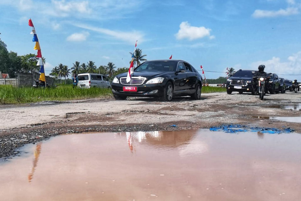 Saat melintas, jendela mobil juga tidak tertutup sehingga terlihat Jokowi meninjau jalan rusak tersebut, sembari membagikan cenderamata kepada penduduk setempat.
