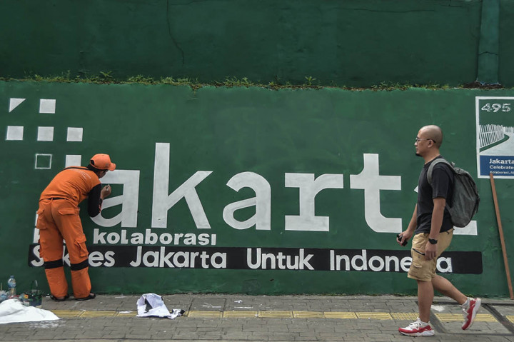 Petugas Penanganan Prasarana dan Sarana Umum (PPSU) Kelurahan Cipete Utara, Kebayoran Baru, Jakarta Selatan mengecat dan melukis ulang mural slogan Kota Jakarta di Jalan RS Fatmawati Raya, Jakarta Selatan, Sabtu, 6 Mei 2023.