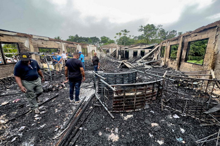 Penyelidik dan pegawai pemerintah memeriksa asrama sekolah yang hangus terbakar dan menewaskan sedikitnya 20 orang di Mahdia, Guyana pada Senin, 22 Mei 2023.