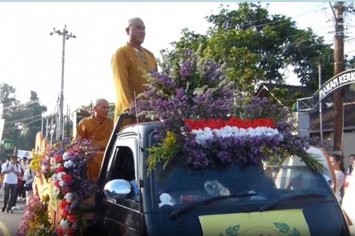 Masyarakat sekitar tumpah ruah ke jalan. Mereka menyemangati peserta pawai dan mengabadikan momen tersebut dengan gawai masing-masing.