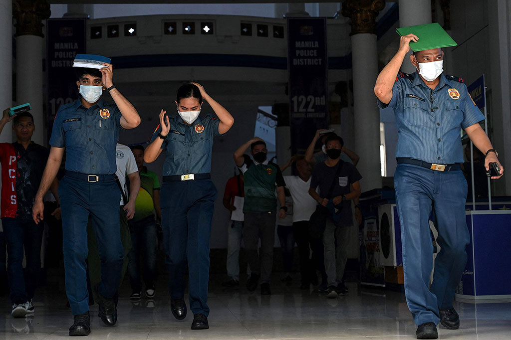 Orang-orang bergegas keluar dari gedung markas polisi di Manila pada Kamis, 15 Juni 2023, setelah gempa berkekuatan magnitudo 6,2 melanda Filipina.
