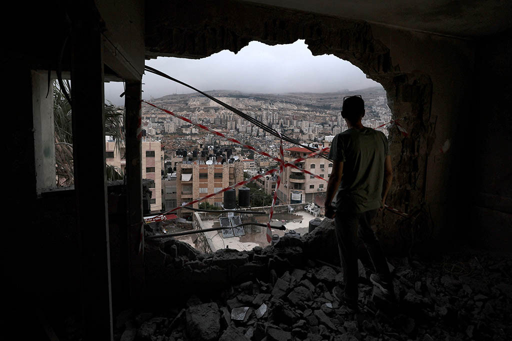 Seorang jurnalis AFP melihat sekelompok pemuda mengamati kerusakan apartemen setelah fajar pada hari Kamis. Logam bengkok dan tumpukan puing berserakan di lantai dan lubang menganga tertinggal di dinding.