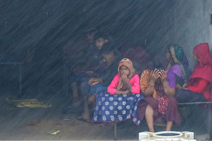 Sebuah keluarga berlindung di sebuah toko yang ditinggalkansaat topan Biparjoy mendarat di kota pesisir Mandvi, India, Jumat, 16 Juni 2023.