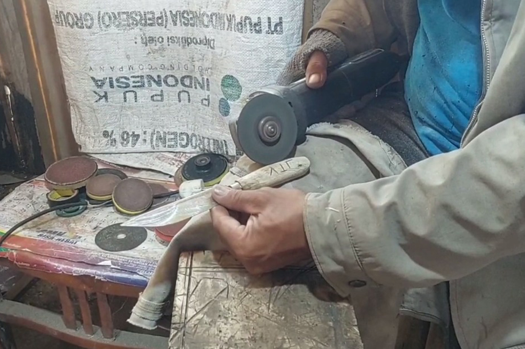 Di halaman depan rumahnya yang digunakan untuk etalase serta tempat produksi Roni mengerjakan pesanan pisau dari sejumlah pelanggan.