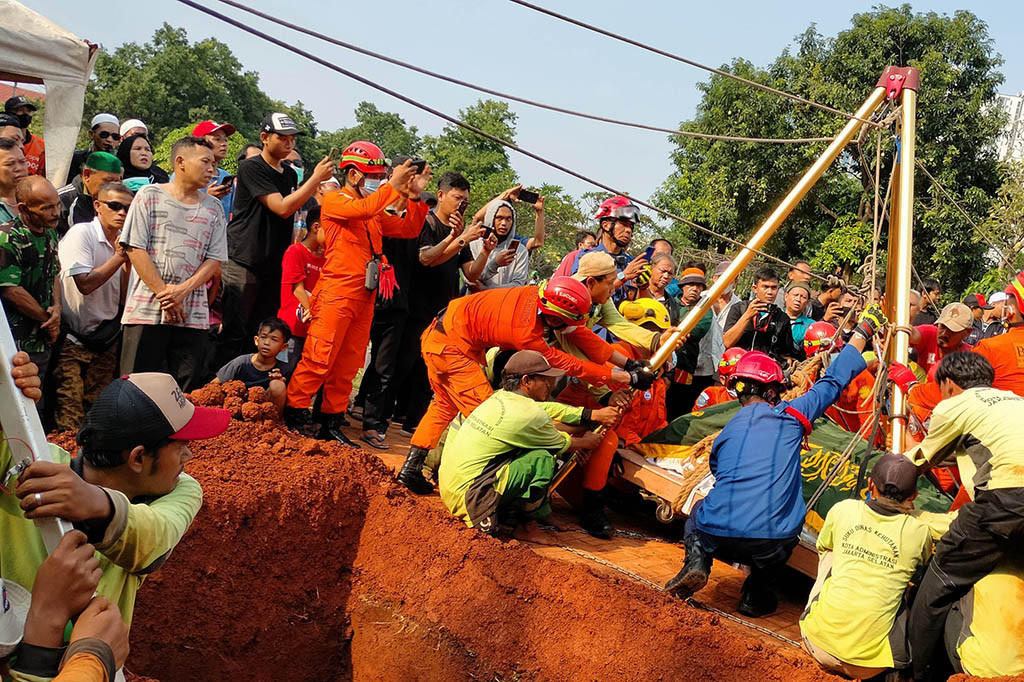 Petugas pemadaman kebakaran dan Basarnas dengan dibantu warga menurunkan jenazah M Fajri Rifana, pria obesitas berbobot 300 kg saat dimakamkan di TPU Menteng Pulo, Jakarta, Kamis, 22 Juni 2023. 
