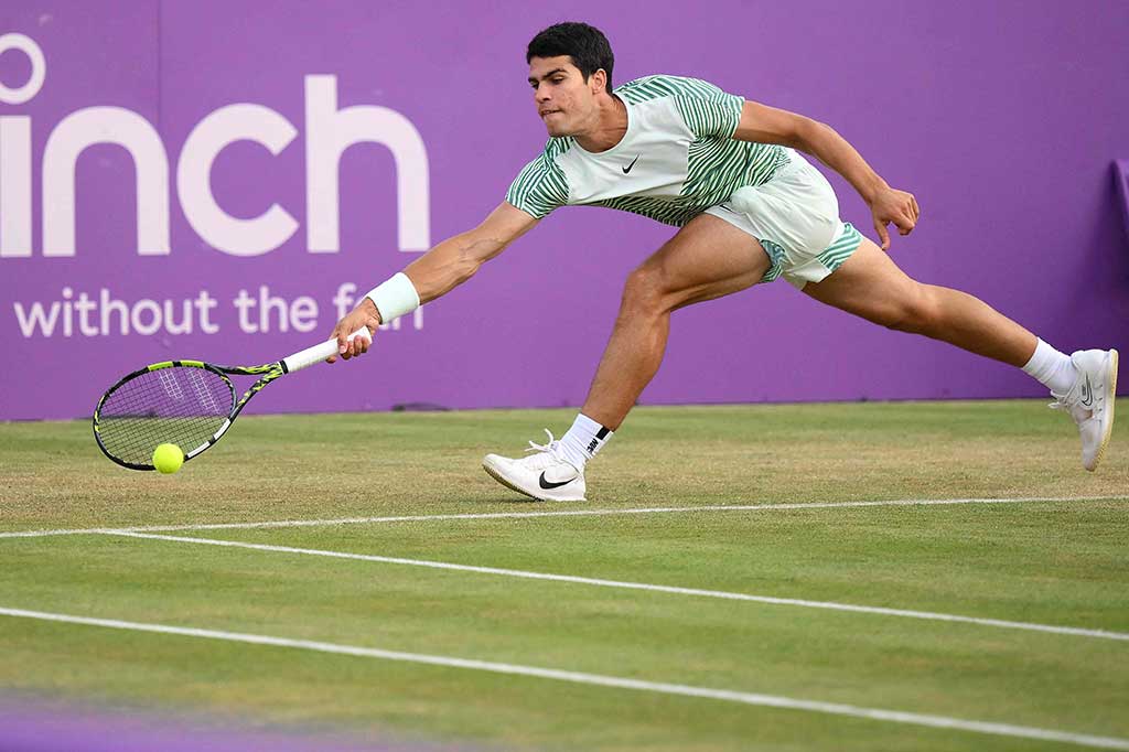 Petenis Spanyol Carlos Alcaraz mencoba mengembalikan bola ke arah petenis Bulgaria Grigir Dimitrov pada babak perempat final Cinch ATP di Queen's Club, London, Jumat, 23 Juni 2023 waktu setempat.