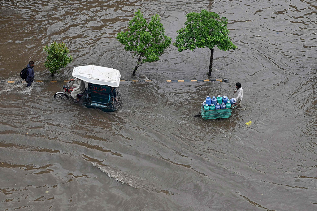 Orang-orang melewati jalan yang tergenang air setelah hujan lebat di Lahore, Pakistan, Senin, 26 Juni 2023. Sedikitnya 20 orang tewas dalam waktu 24 jam terakhir ketika hujan pramusim hujan dan banjir bandang melanda Provinsi Punjab, Pakistan.