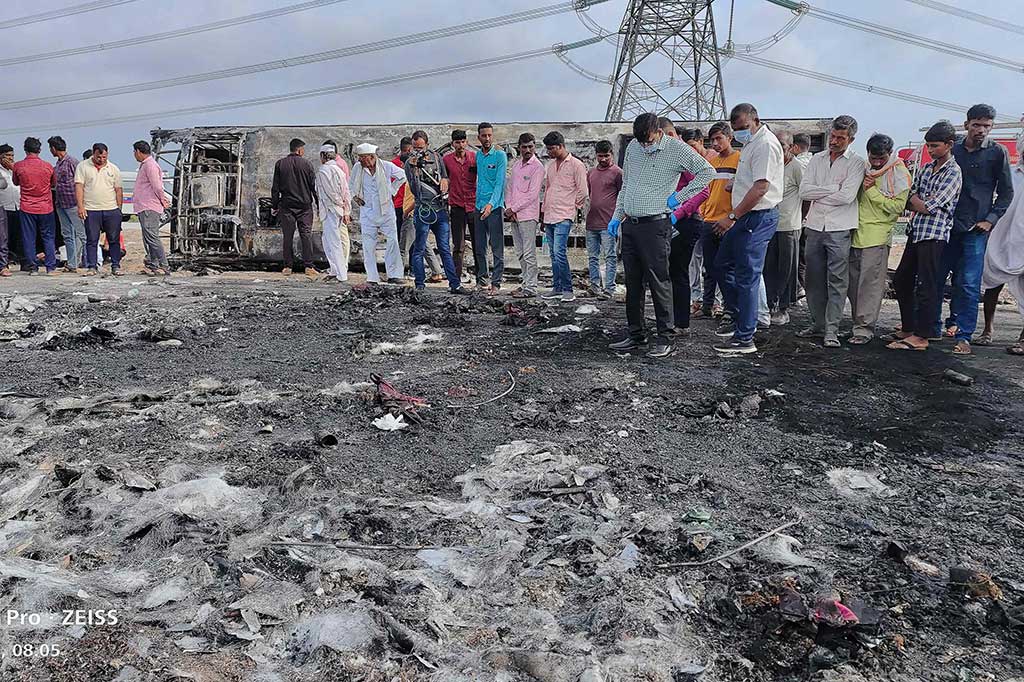Orang-orang berkumpul di samping sisa-sisa bus (latar belakang) yang terbakar di sepanjang Jalan Tol Samruddhi dekat Sindkhed Raja di distrik Buldhana negara bagian Maharashtra pada Sabtu, 1 Juli 2023. Sedikitnya 25 orang tewas dan delapan lainnya luka-luka setelah sebuah bus terbakar semalam di jalan tol di negara bagian Maharashtra India.