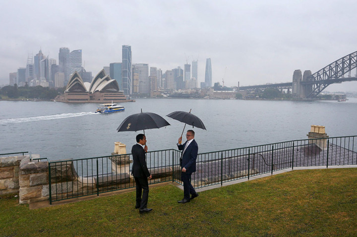 Tampak kedua pemimpin berbincang dengan akrab dan saling memegang payung senada berwarna hitam sambil berbincang.