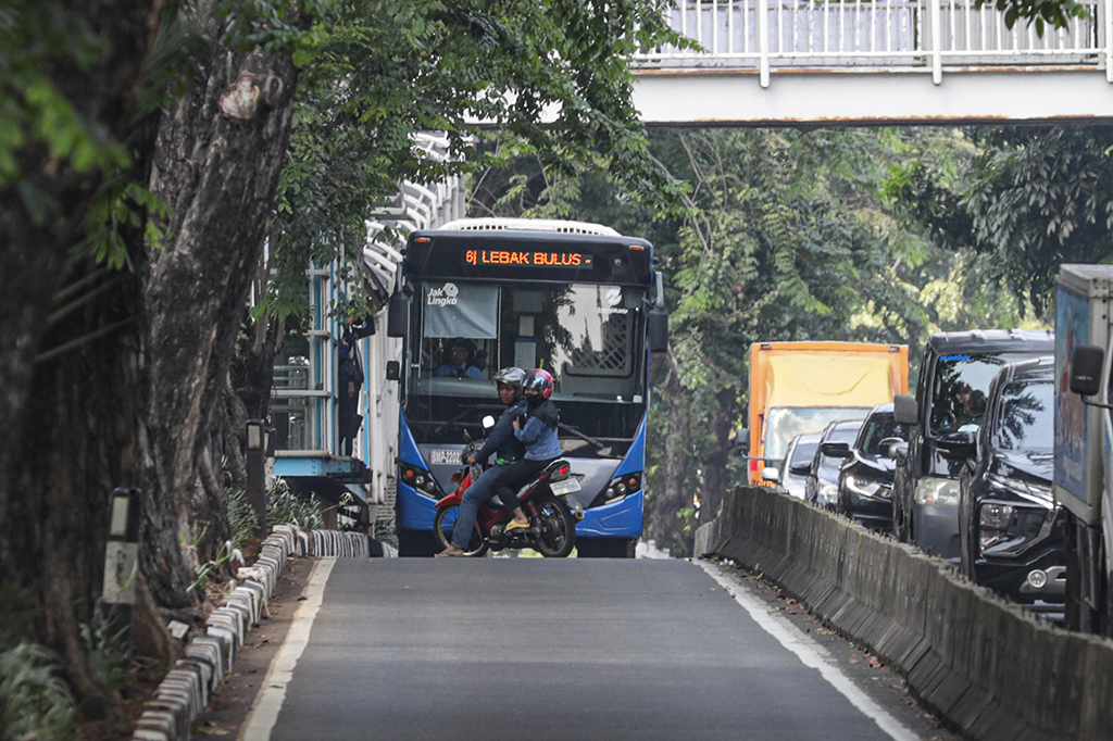 Pengendara sepeda motor nekat memutar balik melawan arah untuk menghindari razia polisi saat masik di jalur bus TransJakarta, namun saat putar balik pengendara motor tersebut terhalang bus TransJakarta hingga akhirnya memutar balik lagi, di kawasan Alteri Pondok Indah, Jakarta Selatan, Rabu, 5 Juli 2023. 