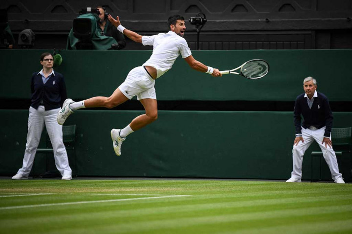 Novak Djokovic melompat saat berusaha mengembalikan bola ke arah petenis Rusia Andrey Rublev pada perempat final Wimbledon, di The All England Tennis Club, Wimbledon, Selasa, 11 Juli 2023 waktu setempat.