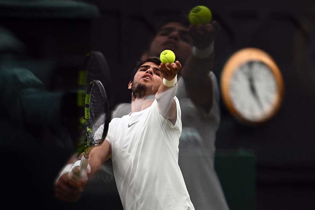 Petenis Spanyol Carlos Alcaraz melancarkan servis ke arah lawannya Daniil Medvedev pada laga semifinal Wimbledon di Wimbledon, London, Jumat, 14 Juli 2023.