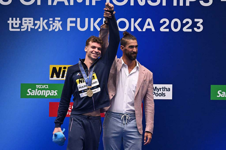 Phelps, atlet Olimpiade paling berprestasi sepanjang masa dengan rekor 28 medali, hadir untuk mempersembahkan Marchand dengan emasnya di Kejuaraan Dunia Akuatik tahun ini.